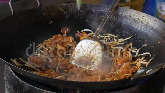 在街上的市场上用虾和蔬菜在炒锅里煮薯条面条4k视频的预览图