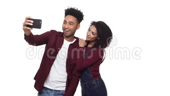 年轻的非裔美国夫妇喜欢玩手机和自拍与夫妇在白色工作室背景视频的预览图