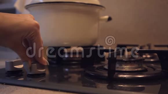 女性手在肮脏的预算厨房里用昏暗的灯光打开煤气灶视频的预览图