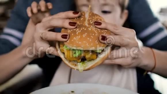 妈妈给孩子喂一个美味的汉堡包芝士汉堡视频的预览图