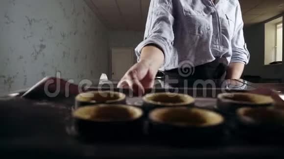 一个糖果女人从烤箱里拿出烘焙的包裹作为甜点馅饼现代厨房烹饪大师班视频的预览图