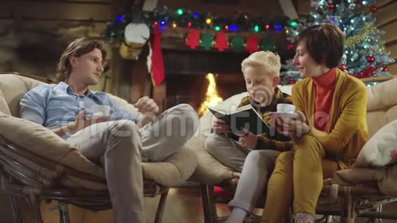 小男孩在圣诞节晚上喝咖啡和聊天时大声读书视频的预览图