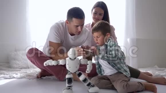 教育玩具现代儿童玩自动机器人遥控智能手机爸爸妈妈坐在地板上视频的预览图