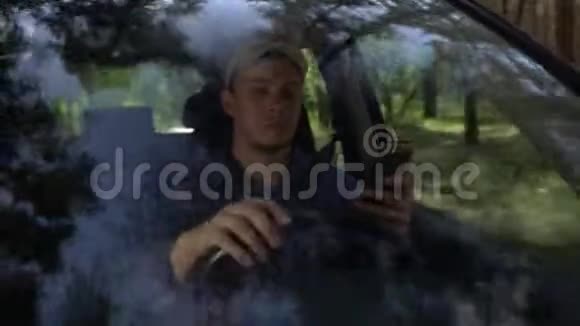 夏天年轻人围着车在森林边开车使用智能手机视频的预览图