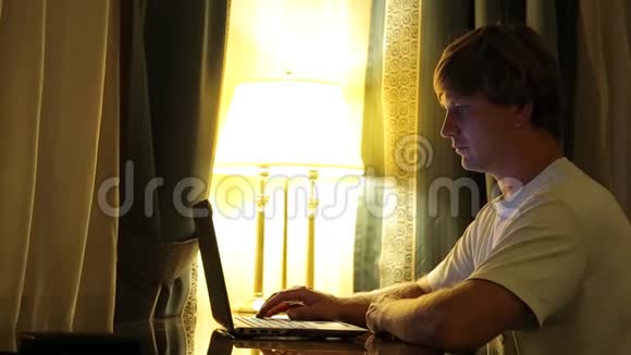 年轻迷人的男人用笔记本电脑在客厅工作的肖像视频的预览图