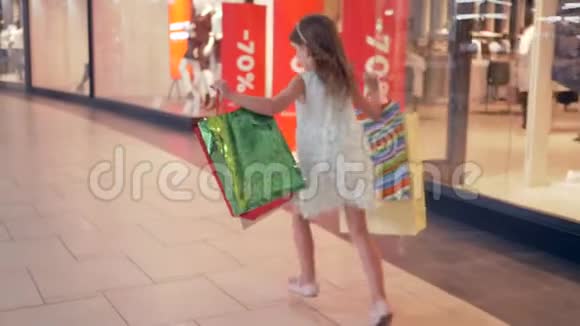 购物日在时尚精品店购买后手里拿着包裹的快乐女孩穿过购物中心视频的预览图