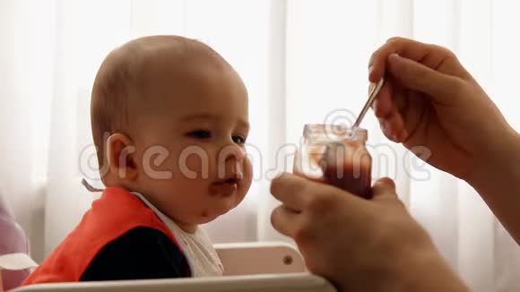 一个年轻快乐的父亲缓慢地喂养他的儿子婴儿水果泥视频的预览图