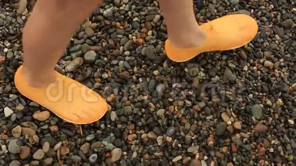 一个青少年的腿在珊瑚拖鞋在鹅卵石海滩保护腿时休息在海洋视频的预览图