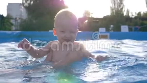 阳光下的孩子很开朗年轻的妈妈在教他游泳时把小儿子从水里抱起来视频的预览图