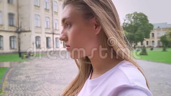 一幅美丽的白种人女孩的特写肖像镜头里看着站在街道上轻松城市的景色视频的预览图