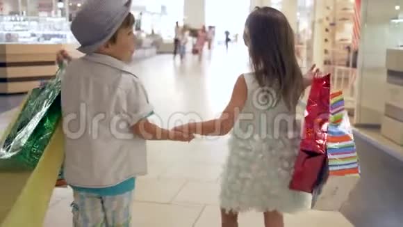 购物销售小哥哥和姐姐一起带着很多包裹购物后牵着手在商场散步视频的预览图