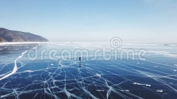 人们旅游步行走在光滑的表面上美丽的贝加尔湖裂缝蓝色的光滑的清澈的冰的腐殖质的雪的雪的视频的预览图