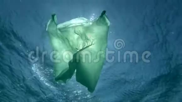 慢运动绿色塑料袋在阳光下慢慢地漂浮在水下表面海洋的塑料污染视频的预览图