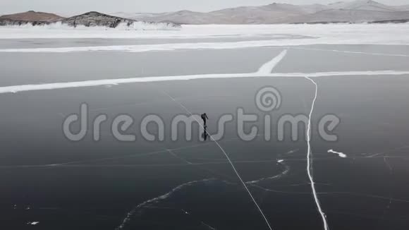 人们旅游步行走在光滑的表面上美丽的贝加尔湖裂缝蓝色的光滑的清澈的冰的腐殖质的雪的雪的视频的预览图