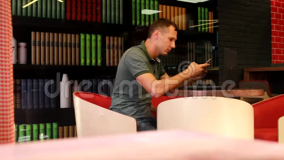 男人坐在办公桌前拿着手机和笔记本电脑视频的预览图