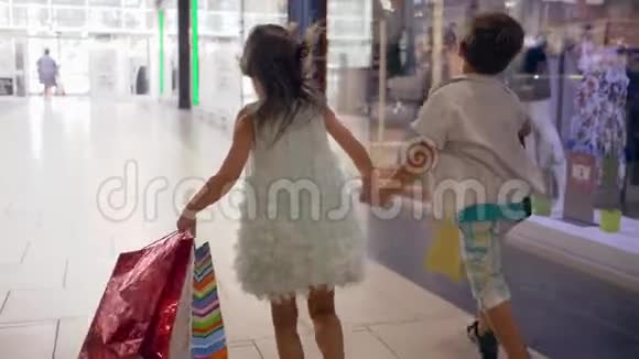 购物假期小弟小妹手拿大包小包在商场购物时玩得开心视频的预览图
