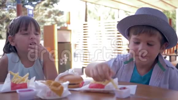 提供外卖食品快乐的朋友孩子们午餐时在街边咖啡馆里吃炸薯条和酱汁视频的预览图