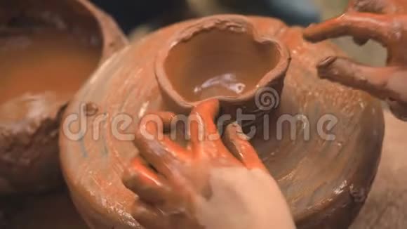 旋转陶工的车轮和粘土器皿从上面一个小孩用陶工上的泥杯雕刻他手视频的预览图