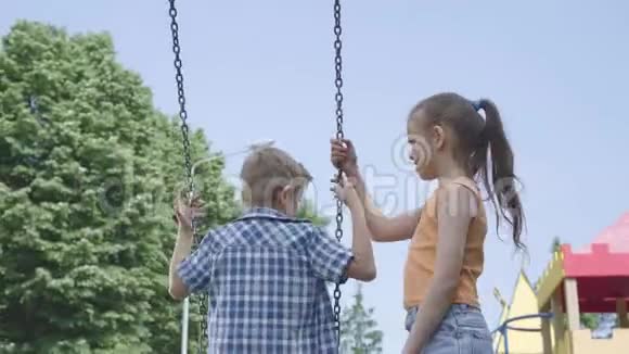 可爱的女孩长发摆动在一个摇摆可爱的男孩户外几个快乐的孩子有趣的无忧无虑的孩子视频的预览图