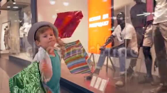 时尚的童年快乐的小男孩手里拿着包裹在昂贵的购买后穿过购物中心视频的预览图