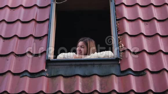 一个女人从敞开的窗户望着街道双手放在窗台上视频的预览图