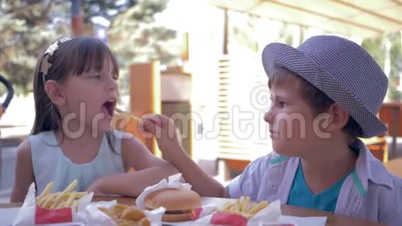 在街头快餐店的午餐期间孩子们吃垃圾餐照顾可爱的男孩给女朋友吃炸薯条视频的预览图