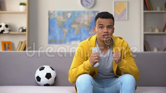 情绪激动的非裔美国青少年在电视上看足球赛国家队视频的预览图