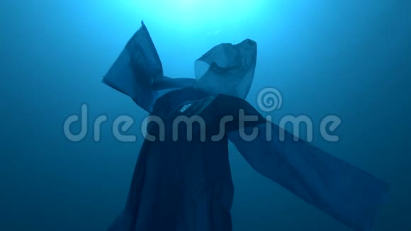 蓝色塑料雨衣作为幽灵慢慢漂浮在蓝色的水中海底塑料污染海洋视频的预览图