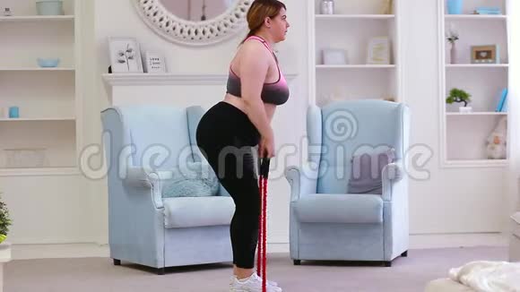 这个模特是一个胖女人在家里减肥和一个扩张器一起做运动视频的预览图