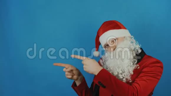 圣诞节和新年像圣诞老人一样的人指向一个文字的地方复制空间蓝色背景视频的预览图