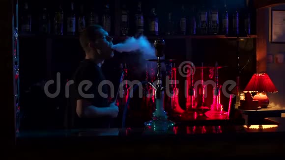 一个年轻人在黑暗的背景上在一个钩子酒吧里抽烟动作缓慢视频的预览图