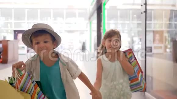 在昂贵的精品店买完东西后孩子们手里拿着购物袋在商场里跑来跑去开心地微笑着视频的预览图