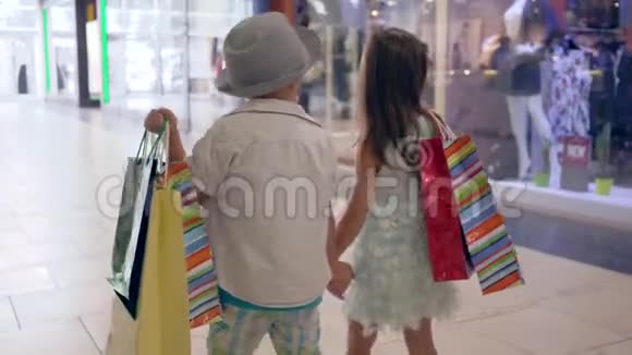 折扣季节小男孩带着女朋友在时尚商店买了包裹后看着商店的橱窗视频的预览图