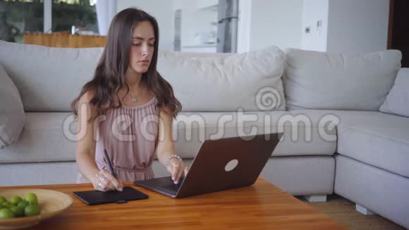 漂亮的女性自由职业者在照明房里用笔记本电脑和平板电脑工作视频的预览图