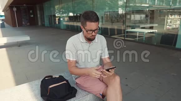 人类正坐在城市的长椅上使用带有wifi的智能手机视频的预览图
