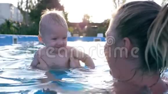 快乐的小男孩和他的妈妈在蓝水游泳池里嬉笑打闹视频的预览图