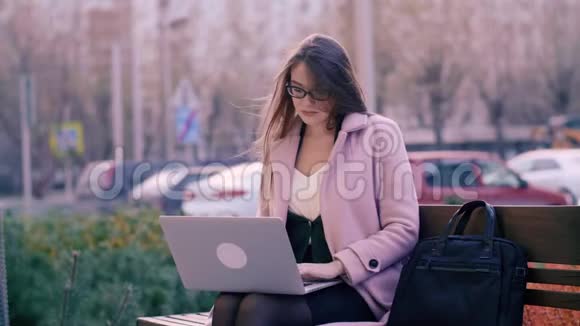 在公园里坐在长椅上时集中精力使用笔记本电脑视频的预览图