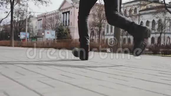 男人的双腿穿着靴子沿着城市街道奔跑视频的预览图