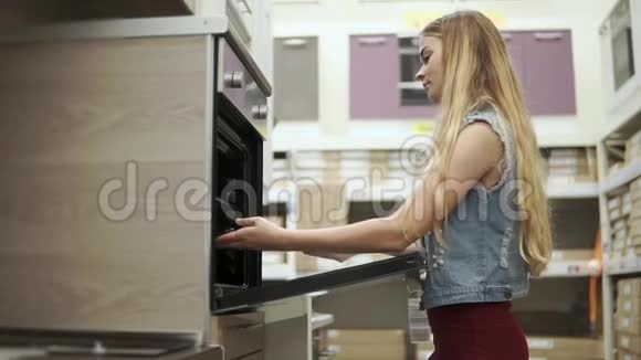 金发女孩正在商店里检查一个带烤箱的现代炊具视频的预览图