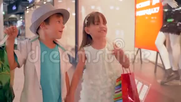 季节性销售带购物套餐的快乐儿童朋友通过商店橱窗在精品店里佩戴人体模型视频的预览图