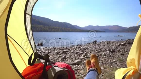 女旅行者躺在湖边的一个黄色帐篷里然后这个女人用旅游棒和视频的预览图
