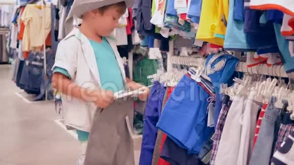 小顾客男孩在打折时挑选时装店的新衣服视频的预览图