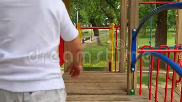 镜头跟随男孩滚下操场上的小山快乐的孩子在公园的游乐场玩耍视频的预览图