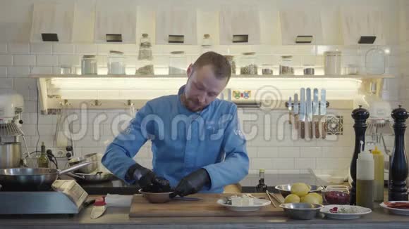 厨师穿着餐厅制服戴着黑色手套站在现代化的厨房里周围有许多厨房用具视频的预览图