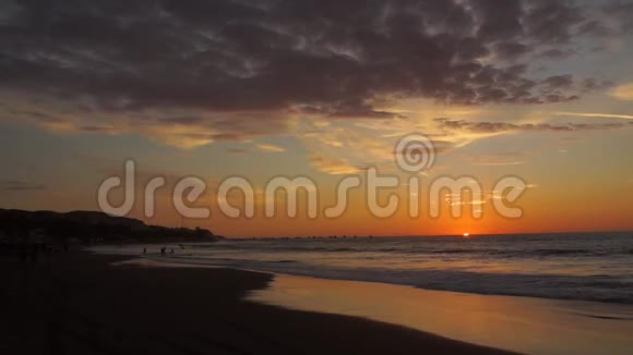 当太阳躲在地平线上时海滩上多云的日落的全景视频的预览图