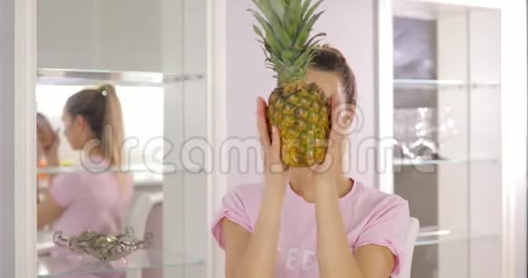 年轻风趣的女人在厨房里玩菠萝视频的预览图