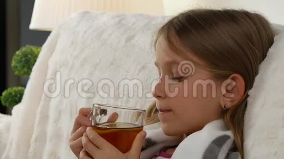 生病的儿童肖像喝柠檬茶悲伤的病女脸在床上沙发4K视频的预览图
