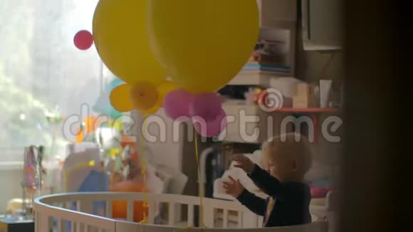 一个小女孩站在婴儿床上玩气球视频的预览图
