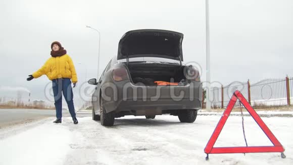 汽车故障紧急信号下雪的乡间公路上的汽车故障一个年轻女子试图赶上汽车视频的预览图