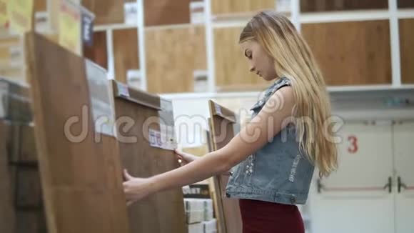 金发女人正在一家商店里摸一块大木板用来做地板覆盖物视频的预览图
